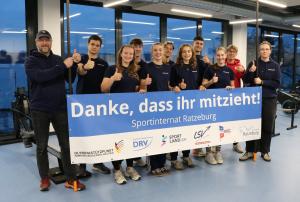 eine Gruppe Jugendlicher streckt die Daumen nach oben und ein Banner hängt davor auf dem steht "Danke, dass ihr mitzieht"  