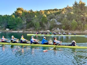 Athleten sitzen im Ruderboot vor Naturkulisse 