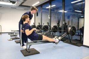 Athleten trainieren im Fitnessraum am Ergometer