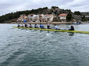 Athleten fahren auf einem See an einer Siedlung vorbei