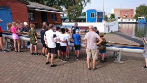 Ruder-Sommerferien-Zeltlager der RV Bille 2018: Betreuer erklärt Kindern ein Ruderboot